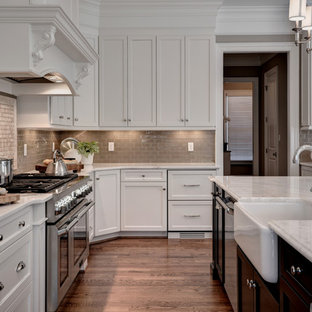 Inspiration for an expansive transitional l-shaped eat-in kitchen in Other with a farmhouse sink, shaker cabinets, white cabinets, marble benchtops, beige splashback, glass tile splashback, stainless steel appliances, medium hardwood floors, with island and brown floor.