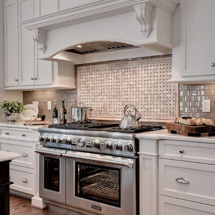 Inspiration for an expansive traditional l-shaped eat-in kitchen in Other with a farmhouse sink, shaker cabinets, white cabinets, marble benchtops, beige splashback, glass tile splashback, stainless steel appliances, medium hardwood floors, with island and brown floor.