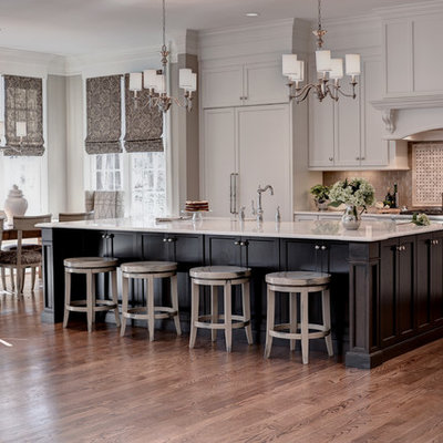 Huge transitional l-shaped medium tone wood floor and brown floor eat-in kitchen photo in Other with a farmhouse sink, shaker cabinets, white cabinets, marble countertops, beige backsplash, glass tile backsplash, stainless steel appliances and an island