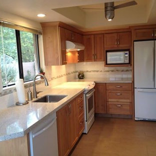 Photo of a mid-sized transitional l-shaped eat-in kitchen in Phoenix with an undermount sink, shaker cabinets, medium wood cabinets, recycled glass benchtops, white splashback, porcelain splashback and white appliances.