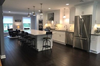 Mid-sized transitional medium tone wood floor eat-in kitchen photo in Newark with recessed-panel cabinets, white cabinets, quartz countertops, ceramic backsplash, stainless steel appliances and an island
