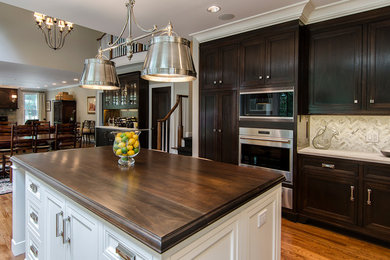 Open concept kitchen - large transitional u-shaped dark wood floor open concept kitchen idea in New York with an undermount sink, recessed-panel cabinets, dark wood cabinets, quartzite countertops, white backsplash, stone tile backsplash, paneled appliances and an island