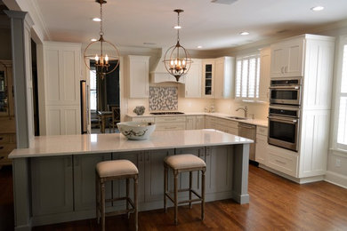 Example of a large transitional u-shaped dark wood floor open concept kitchen design in Other with an undermount sink, recessed-panel cabinets, gray cabinets, quartz countertops, white backsplash, ceramic backsplash, stainless steel appliances, an island and white countertops