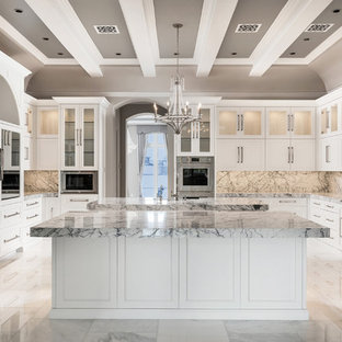 This is an example of an expansive transitional u-shaped separate kitchen in Phoenix with a farmhouse sink, raised-panel cabinets, white cabinets, marble benchtops, multi-coloured splashback, marble splashback, stainless steel appliances, marble floors, multiple islands, multi-coloured floor and multi-coloured benchtop.