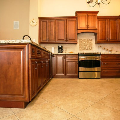 Mid-sized transitional u-shaped porcelain tile eat-in kitchen photo in Miami with an undermount sink, raised-panel cabinets, brown cabinets, granite countertops, beige backsplash, stone tile backsplash, stainless steel appliances and a peninsula