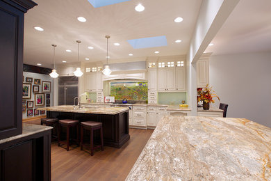 Photo of a large classic enclosed kitchen in Chicago with a submerged sink, raised-panel cabinets, white cabinets, granite worktops, stainless steel appliances, medium hardwood flooring and an island.