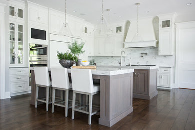 Inspiration for a transitional l-shaped dark wood floor and brown floor eat-in kitchen remodel in Chicago with shaker cabinets, medium tone wood cabinets, white backsplash, stainless steel appliances, two islands and white countertops