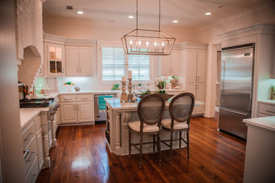 Inspiration for a timeless l-shaped medium tone wood floor and brown floor open concept kitchen remodel in Jackson with a farmhouse sink, beaded inset cabinets, white cabinets, white backsplash, stainless steel appliances and an island