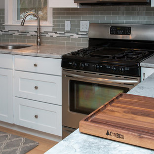 Mid-sized transitional eat-in kitchen ideas - Inspiration for a mid-sized transitional u-shaped light wood floor and brown floor eat-in kitchen remodel in Boston with a single-bowl sink, flat-panel cabinets, white cabinets, granite countertops, gray backsplash, subway tile backsplash, stainless steel appliances, a peninsula and white countertops