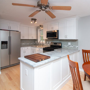 Mid-sized transitional eat-in kitchen inspiration - Example of a mid-sized transitional u-shaped light wood floor and brown floor eat-in kitchen design in Boston with a single-bowl sink, flat-panel cabinets, white cabinets, granite countertops, gray backsplash, subway tile backsplash, stainless steel appliances, a peninsula and white countertops