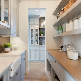 Transitional kitchen pantry appliance - Example of a transitional galley light wood floor and beige floor kitchen pantry design in Minneapolis with a farmhouse sink, shaker cabinets, gray cabinets, brown backsplash, subway tile backsplash and white countertops