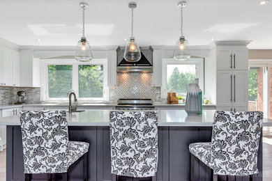 Inspiration for a medium sized traditional l-shaped kitchen/diner in Toronto with a single-bowl sink, shaker cabinets, black cabinets, engineered stone countertops, grey splashback, marble splashback, stainless steel appliances, light hardwood flooring, an island, grey floors and grey worktops.
