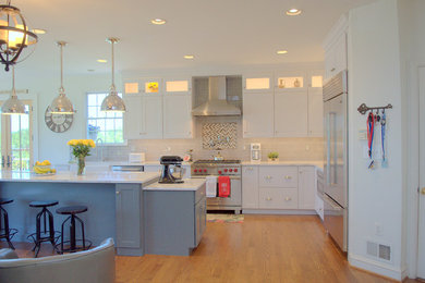 Open concept kitchen - mid-sized transitional l-shaped light wood floor and brown floor open concept kitchen idea in DC Metro with a farmhouse sink, shaker cabinets, white cabinets, white backsplash, subway tile backsplash, stainless steel appliances, an island and marble countertops