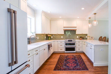 Mid-sized transitional u-shaped medium tone wood floor and brown floor eat-in kitchen photo in Philadelphia with an undermount sink, flat-panel cabinets, white cabinets, quartz countertops, green backsplash, glass tile backsplash, white appliances, a peninsula and white countertops
