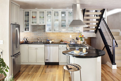 Photo of a medium sized classic u-shaped open plan kitchen in Denver with a submerged sink, recessed-panel cabinets, grey cabinets, granite worktops, multi-coloured splashback, mosaic tiled splashback, stainless steel appliances, light hardwood flooring and a breakfast bar.