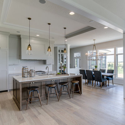 Inspiration for a large transitional l-shaped light wood floor and beige floor eat-in kitchen remodel in Minneapolis with an undermount sink, shaker cabinets, white cabinets, quartzite countertops, white backsplash, ceramic backsplash, paneled appliances, an island and white countertops