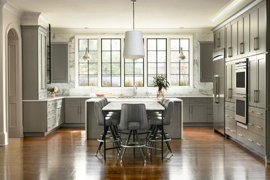 Example of a transitional l-shaped medium tone wood floor and brown floor eat-in kitchen design in Charlotte with shaker cabinets, gray cabinets, white backsplash, stone slab backsplash, stainless steel appliances, an island and white countertops