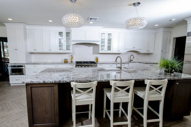 Example of a large transitional u-shaped porcelain tile eat-in kitchen design in New York with a farmhouse sink, shaker cabinets, white cabinets, granite countertops, white backsplash, stainless steel appliances, an island and ceramic backsplash