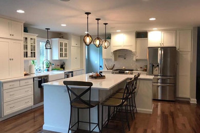 Kitchen - transitional l-shaped kitchen idea in Philadelphia with a farmhouse sink, shaker cabinets, white cabinets, marble countertops, white backsplash, subway tile backsplash, stainless steel appliances and an island