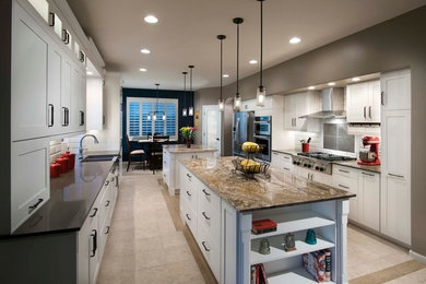Example of a transitional u-shaped ceramic tile eat-in kitchen design in Phoenix with a farmhouse sink, shaker cabinets, white cabinets, granite countertops, white backsplash, ceramic backsplash, stainless steel appliances and two islands
