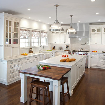 Kitchen - mid-sized traditional dark wood floor kitchen idea in New York with a farmhouse sink, beaded inset cabinets, white cabinets, marble countertops, white backsplash, subway tile backsplash, stainless steel appliances, an island and white countertops
