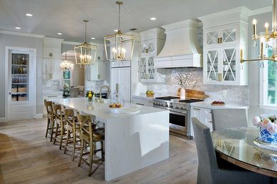 Eat-in kitchen - mid-sized transitional u-shaped light wood floor eat-in kitchen idea in Sacramento with a farmhouse sink, shaker cabinets, white cabinets, quartz countertops, gray backsplash, porcelain backsplash, stainless steel appliances, an island and white countertops