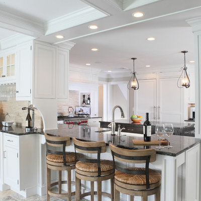 Eat-in kitchen - large transitional u-shaped travertine floor eat-in kitchen idea in New York with recessed-panel cabinets, a farmhouse sink, granite countertops, white cabinets, beige backsplash, stone tile backsplash, paneled appliances and an island