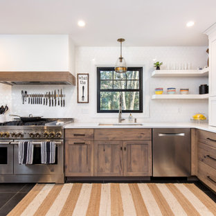Mid-sized transitional l-shaped open plan kitchen in New York with an undermount sink, shaker cabinets, medium wood cabinets, quartz benchtops, white splashback, ceramic splashback, stainless steel appliances, ceramic floors, with island, white benchtop and black floor.