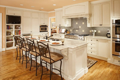 Eat-in kitchen - mid-sized transitional l-shaped medium tone wood floor eat-in kitchen idea in Dallas with a double-bowl sink, shaker cabinets, white cabinets, gray backsplash, ceramic backsplash, stainless steel appliances and an island