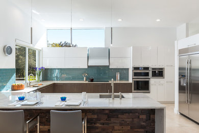 Kitchen - mid-sized contemporary u-shaped travertine floor and beige floor kitchen idea in Tampa with a farmhouse sink, flat-panel cabinets, marble countertops, ceramic backsplash, stainless steel appliances, an island, white cabinets and blue backsplash