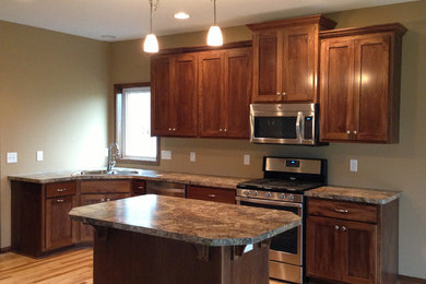 Example of an arts and crafts l-shaped eat-in kitchen design in Minneapolis with a drop-in sink, shaker cabinets, brown cabinets, laminate countertops and stainless steel appliances