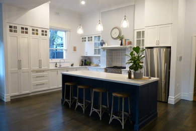 Exempel på ett stort klassiskt kök, med en undermonterad diskho, skåp i shakerstil, vita skåp, bänkskiva i kvarts, vitt stänkskydd, stänkskydd i keramik, rostfria vitvaror, mellanmörkt trägolv, en köksö och brunt golv