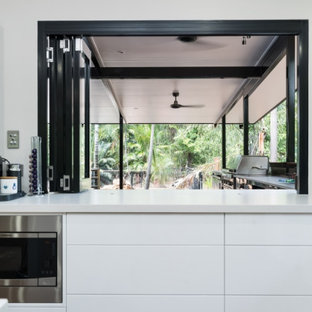 Photo of a tropical kitchen in Darwin with stainless steel appliances, vinyl floors and with island.