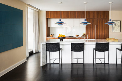 ニューヨークにあるコンテンポラリースタイルのおしゃれなアイランドキッチン (シングルシンク、白いキッチンパネル、パネルと同色の調理設備、黒い床、白いキッチンカウンター) の写真