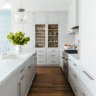 Diseño de cocina clásica renovada, de tamaño medio, con una isla, fregadero bajoencimera, armarios tipo vitrina, puertas de armario grises, electrodomésticos de acero inoxidable y suelo de madera oscura