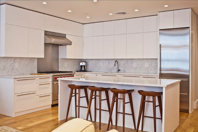 Example of a mid-sized trendy l-shaped medium tone wood floor eat-in kitchen design in New York with flat-panel cabinets, white cabinets, granite countertops, gray backsplash, stone slab backsplash, stainless steel appliances and an island