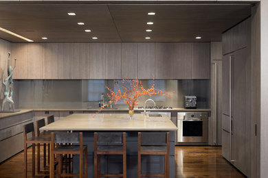 Large minimalist u-shaped dark wood floor and brown floor open concept kitchen photo in New York with a double-bowl sink, flat-panel cabinets, gray cabinets, solid surface countertops, gray backsplash, glass sheet backsplash, paneled appliances and an island
