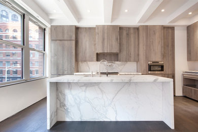 This is an example of a large modern l-shaped kitchen/diner in New York with a built-in sink, flat-panel cabinets, grey cabinets, marble worktops, stone slab splashback, stainless steel appliances, medium hardwood flooring and an island.
