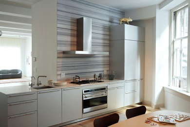 Example of a small trendy single-wall light wood floor eat-in kitchen design in New York with flat-panel cabinets, gray cabinets, no island, an undermount sink, multicolored backsplash and stainless steel appliances