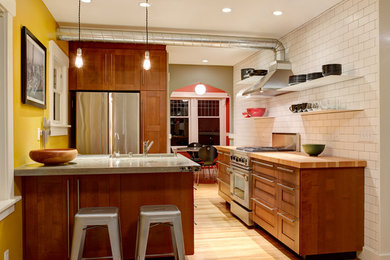 Cette image montre une cuisine design avec un plan de travail en bois, une crédence blanche, une crédence en carrelage métro et un électroménager en acier inoxydable.