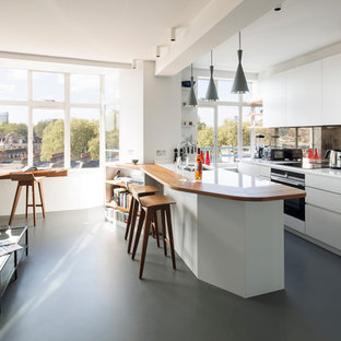 Offene Moderne Küche mit Unterbauwaschbecken, flächenbündigen Schrankfronten, weißen Schränken, Rückwand aus Spiegelfliesen, Linoleum, Halbinsel, grauem Boden und weißen Elektrogeräten in London