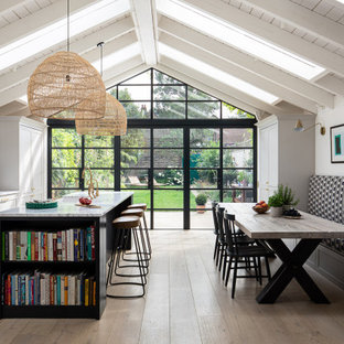 Ispirazione per una grande cucina abitabile chic con lavello stile country, ante in stile shaker, ante grigie, elettrodomestici neri, parquet chiaro, isola, pavimento beige e top bianco