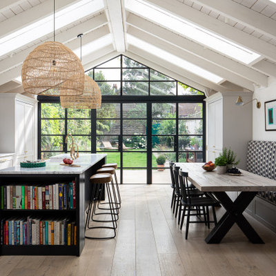 Inspiration for a large transitional light wood floor and beige floor eat-in kitchen remodel in London with a farmhouse sink, shaker cabinets, gray cabinets, black appliances, an island and white countertops