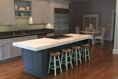 Large minimalist single-wall medium tone wood floor open concept kitchen photo in Nashville with louvered cabinets, gray cabinets, marble countertops, gray backsplash, stainless steel appliances and an island