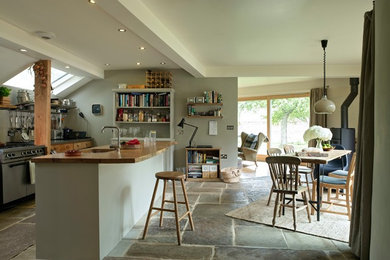 This is an example of a country open plan kitchen in Oxfordshire with slate flooring, an island and brown floors.