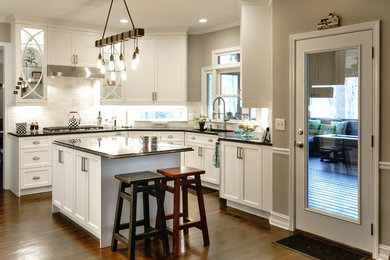 Mid-sized transitional u-shaped dark wood floor and brown floor eat-in kitchen photo in Atlanta with an undermount sink, recessed-panel cabinets, white cabinets, granite countertops, beige backsplash, travertine backsplash, stainless steel appliances, an island and green countertops