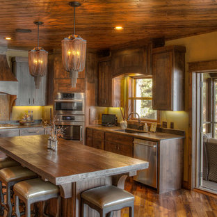 Design ideas for a large country l-shaped kitchen in Minneapolis with an undermount sink, beaded inset cabinets, dark wood cabinets, wood benchtops, multi-coloured splashback, slate splashback, stainless steel appliances, medium hardwood floors, with island, brown floor and brown benchtop.