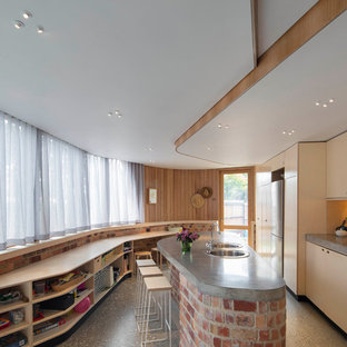 Mid-sized contemporary galley separate kitchen in Melbourne with flat-panel cabinets, light wood cabinets, concrete benchtops, beige splashback, stainless steel appliances, with island, grey floor and timber splashback.