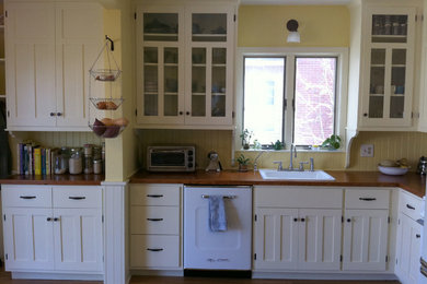 Farmhouse l-shaped medium tone wood floor enclosed kitchen photo in Providence with a drop-in sink, recessed-panel cabinets, white cabinets, wood countertops, yellow backsplash and white appliances