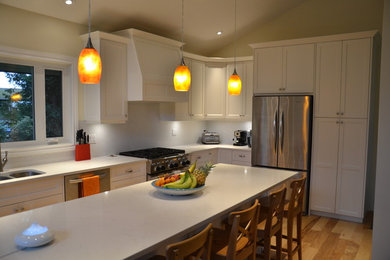 Example of a mid-sized trendy l-shaped light wood floor open concept kitchen design in Vancouver with an undermount sink, shaker cabinets, white cabinets, quartz countertops, white backsplash, ceramic backsplash, stainless steel appliances and an island